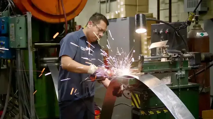 Manufacturing technician grinding metal in a factory